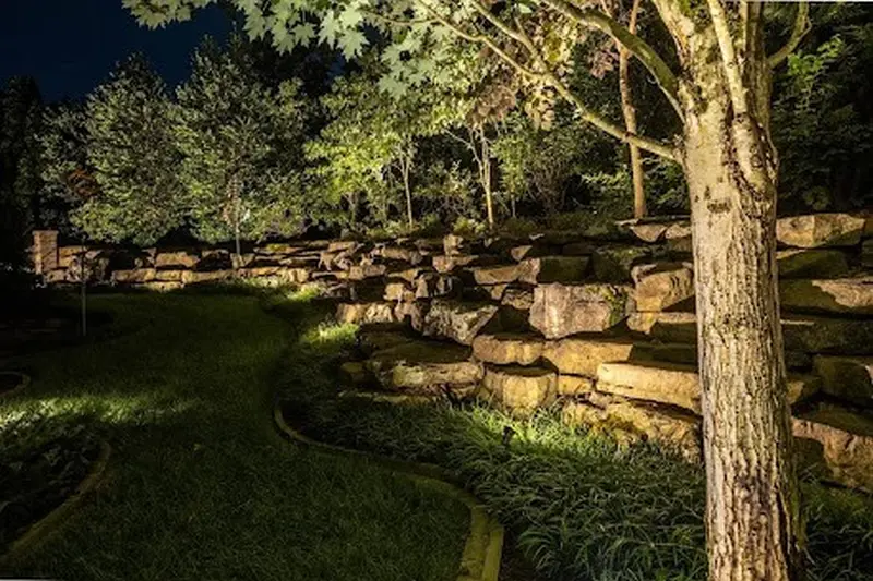 Estate backyard landscape lighting in Barrington Hills, IL featuring natural stone retaining walls, tree uplighting, and moonlighting